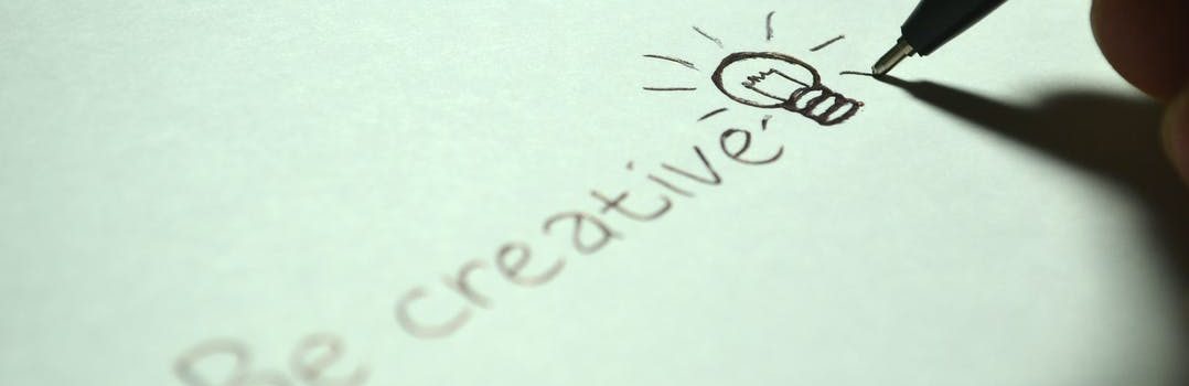 White paper and a pen writing words "Be creative".