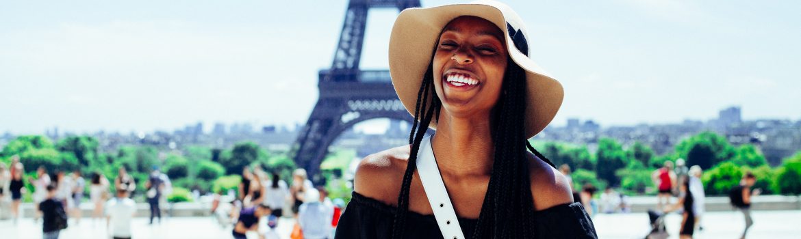 Eiffel tower in Paris and a girl smiling in a black dress.