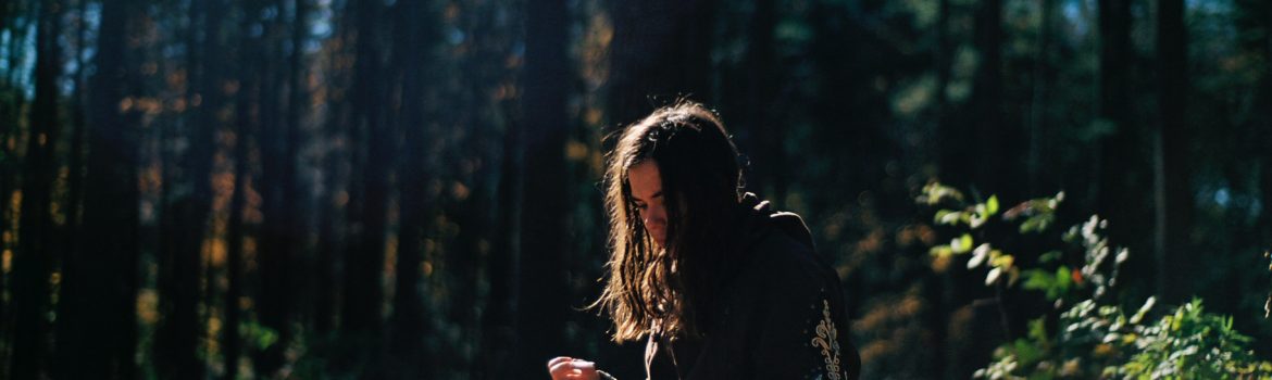 A girl in the forest sitting on stump and making some notes in her book.