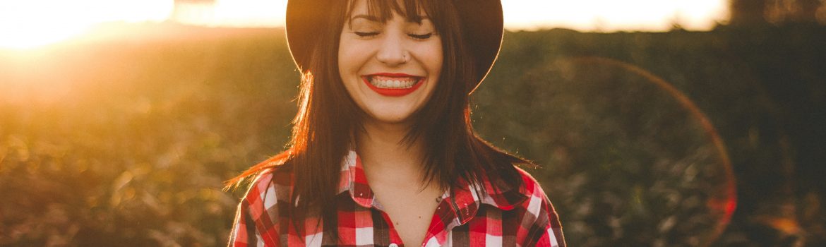 A girl smiling standing with countryside and the sun, dreaming about creative writing program.