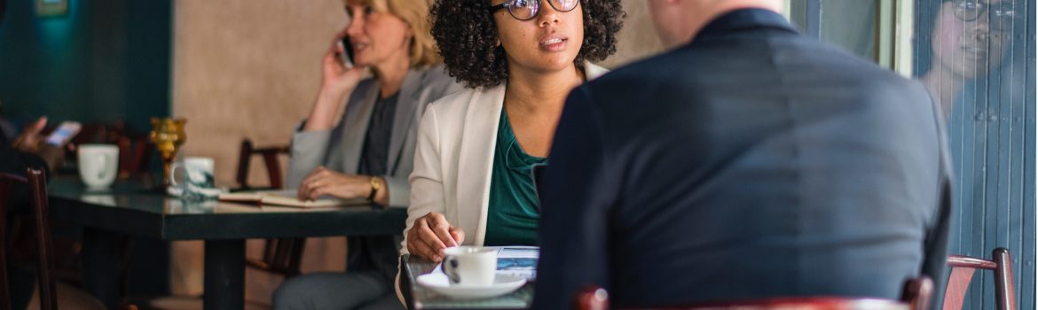 Dialog of a woman in glasses with a man in front, having cup of tea in cafe.