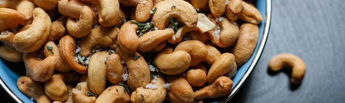 Cashew with salt and herbs on a plate and black table.