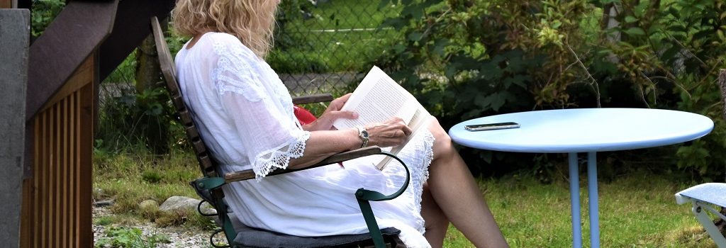 Woman in a white dress reading a book in the garden