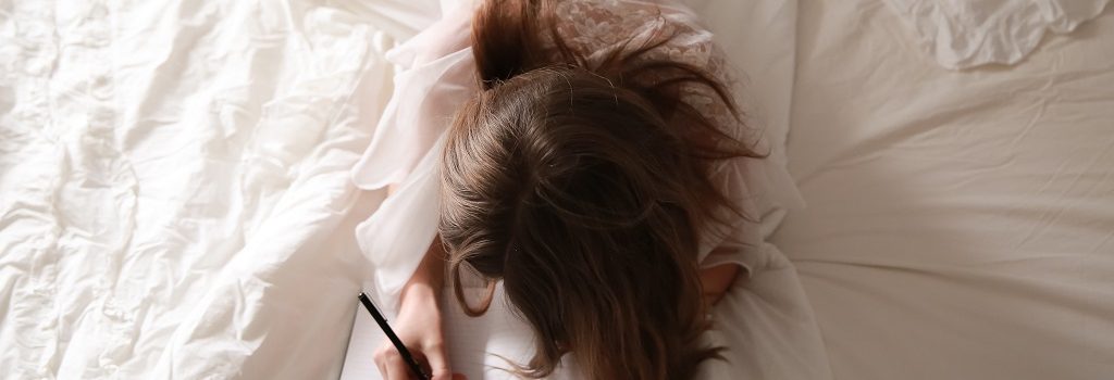 Banner for a post with a girl lying in bed and writing an essay.